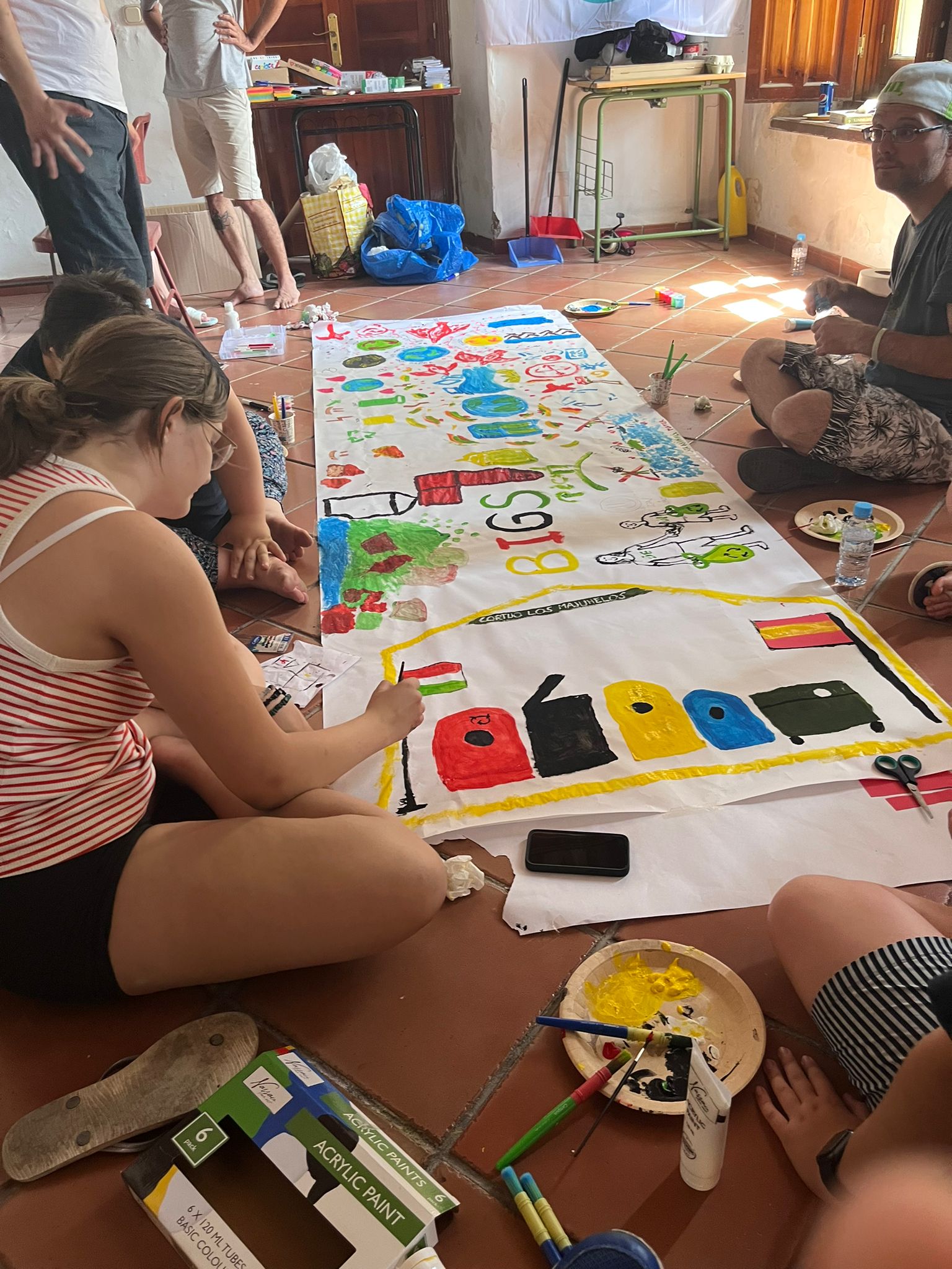 Photo of members of Youth Empowerment in the BIGS Project drawing all together in a banner on the ground